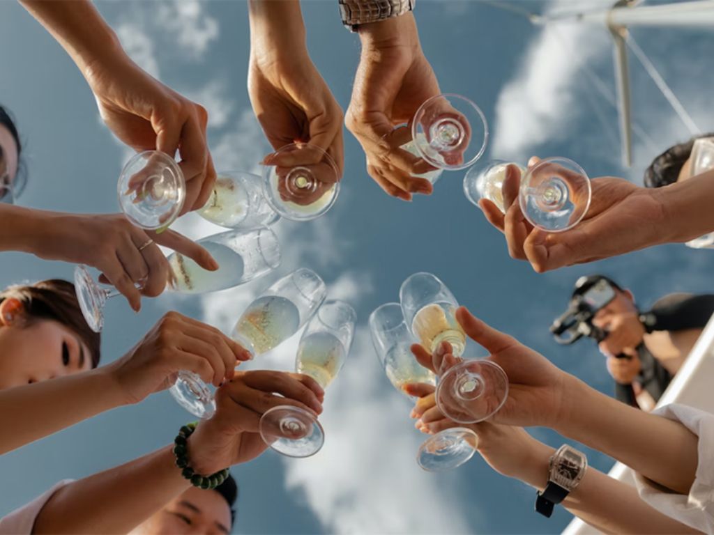 People-holding-clear-glass-bottles-during-daytime