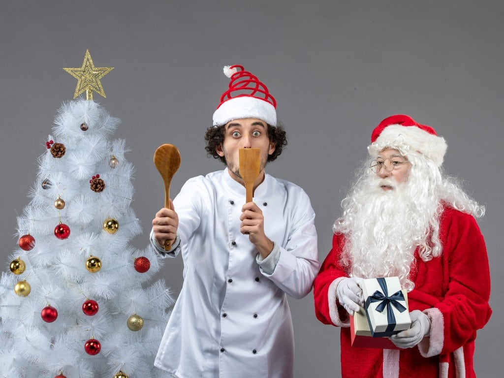 A chef smiling along with Santa Claus.