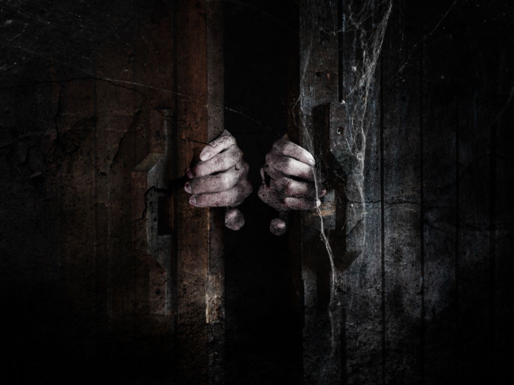 Ghost hands open the wooden door from the inside of the old dark room
